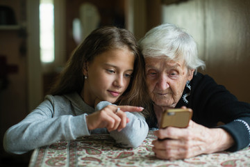 bambina che aiuta anziana ad utilizzare lo smarthphone